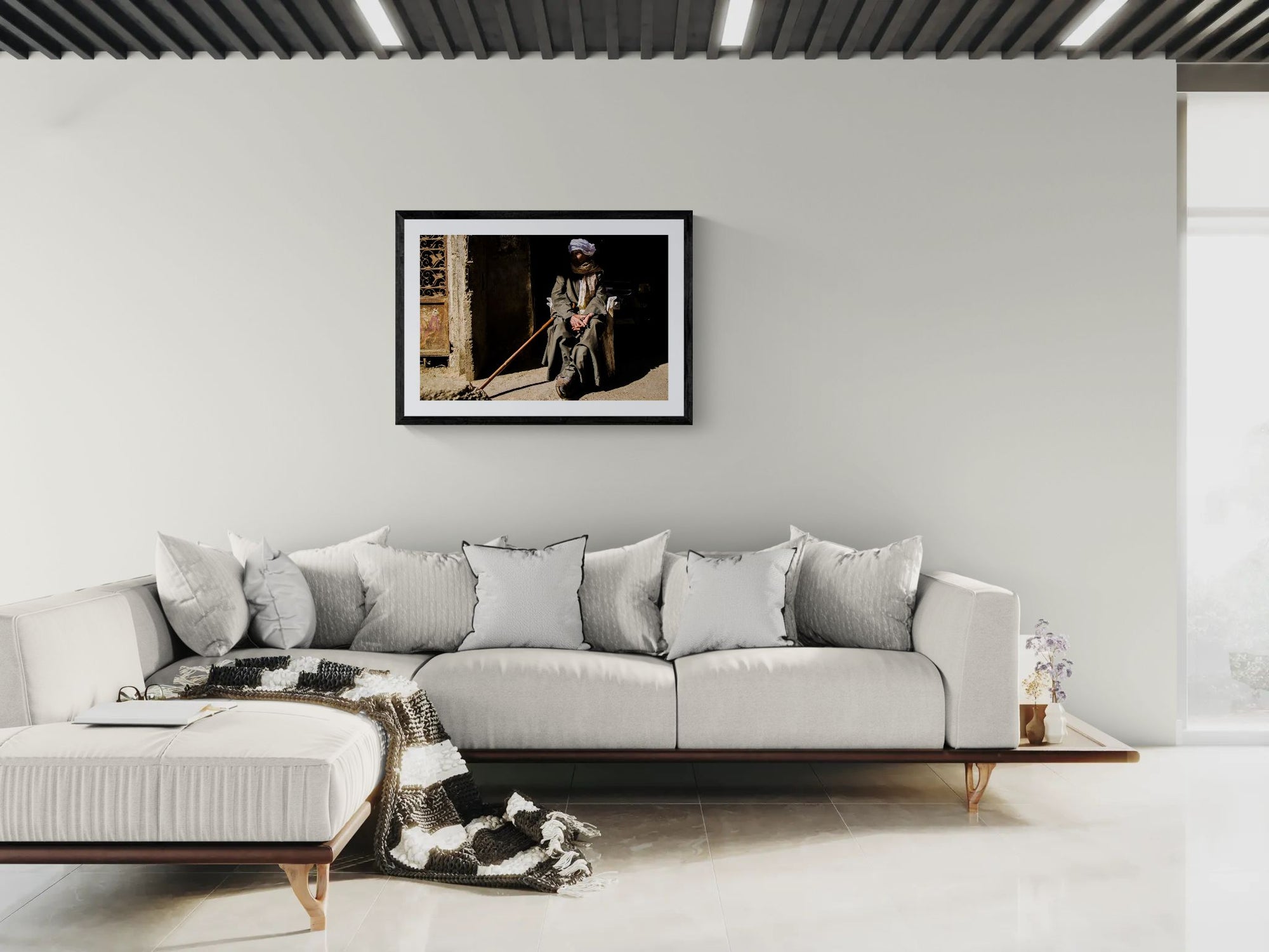 Egypt Old Man with Cane, Cairo's Garbage City framed in black above a terracotta velvet sofa, gray plaster wall — Good Beans NYC.