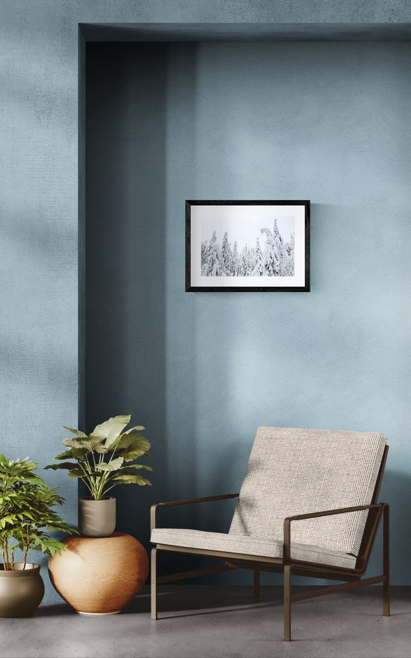 Finland Arctic Circle Snow Forest, Lapland framed in black on a gallery wall with a viewer in a straw hat in front — Good Beans NYC.