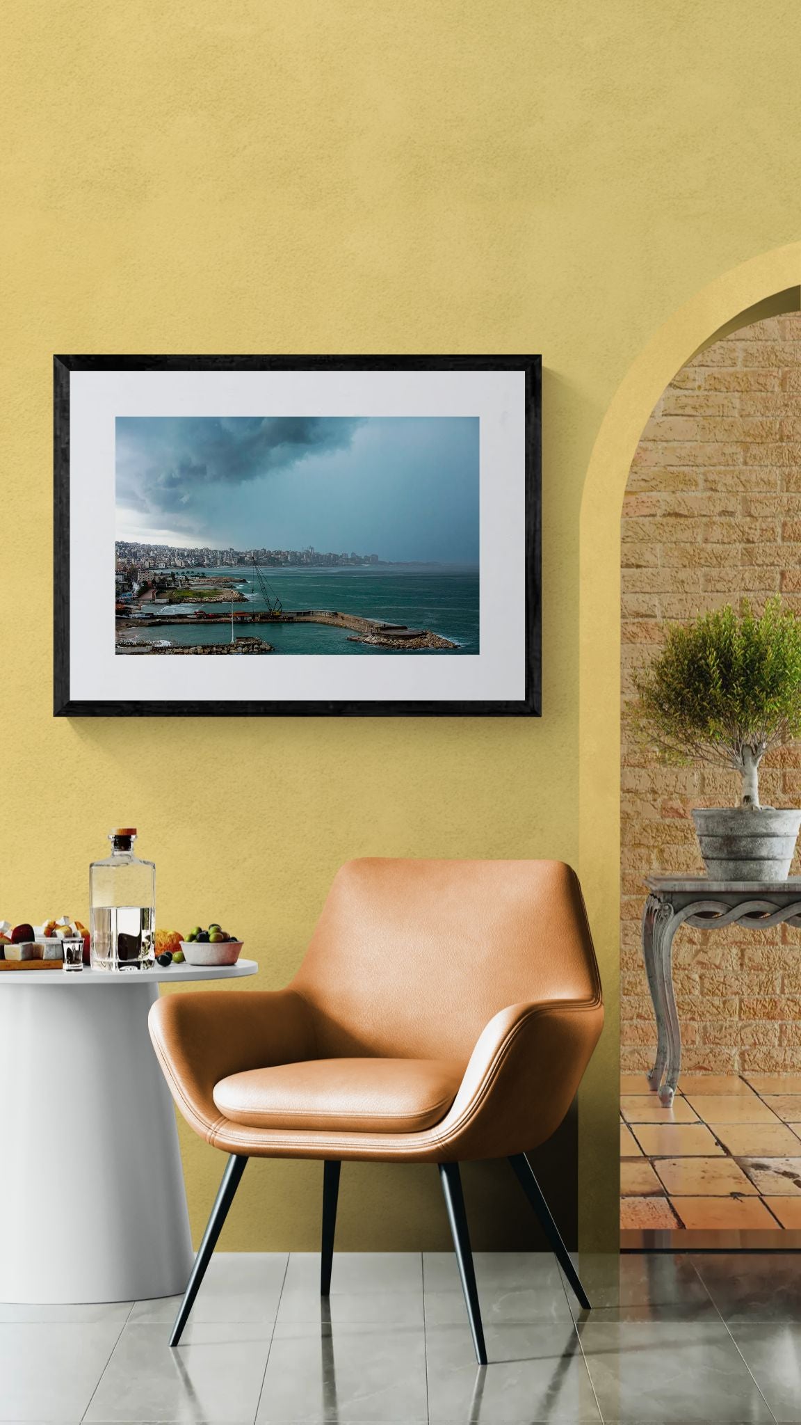 Beirut Storm, Lebanese Coast framed in black above a beige sofa, sunlit yellow plaster wall — Good Beans NYC.