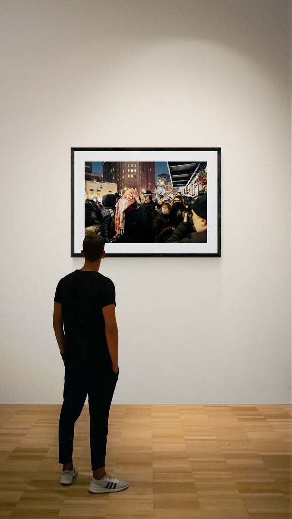 NYC NYPD Megaphone Standoff, Pro Palestine framed in black on a gallery wall with a viewer in a straw hat in front — Good Beans NYC.