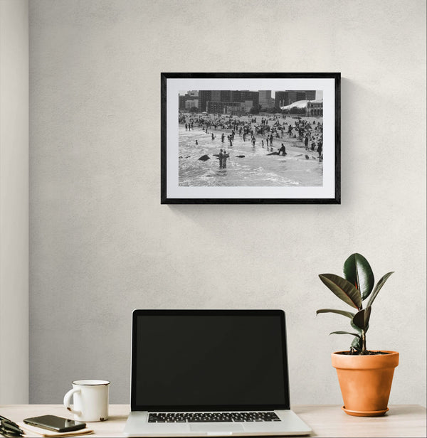 NYC Mermaid Parade Sea Men, Coney Island Surf framed in black above a terracotta velvet sofa, gray plaster wall — Good Beans NYC.