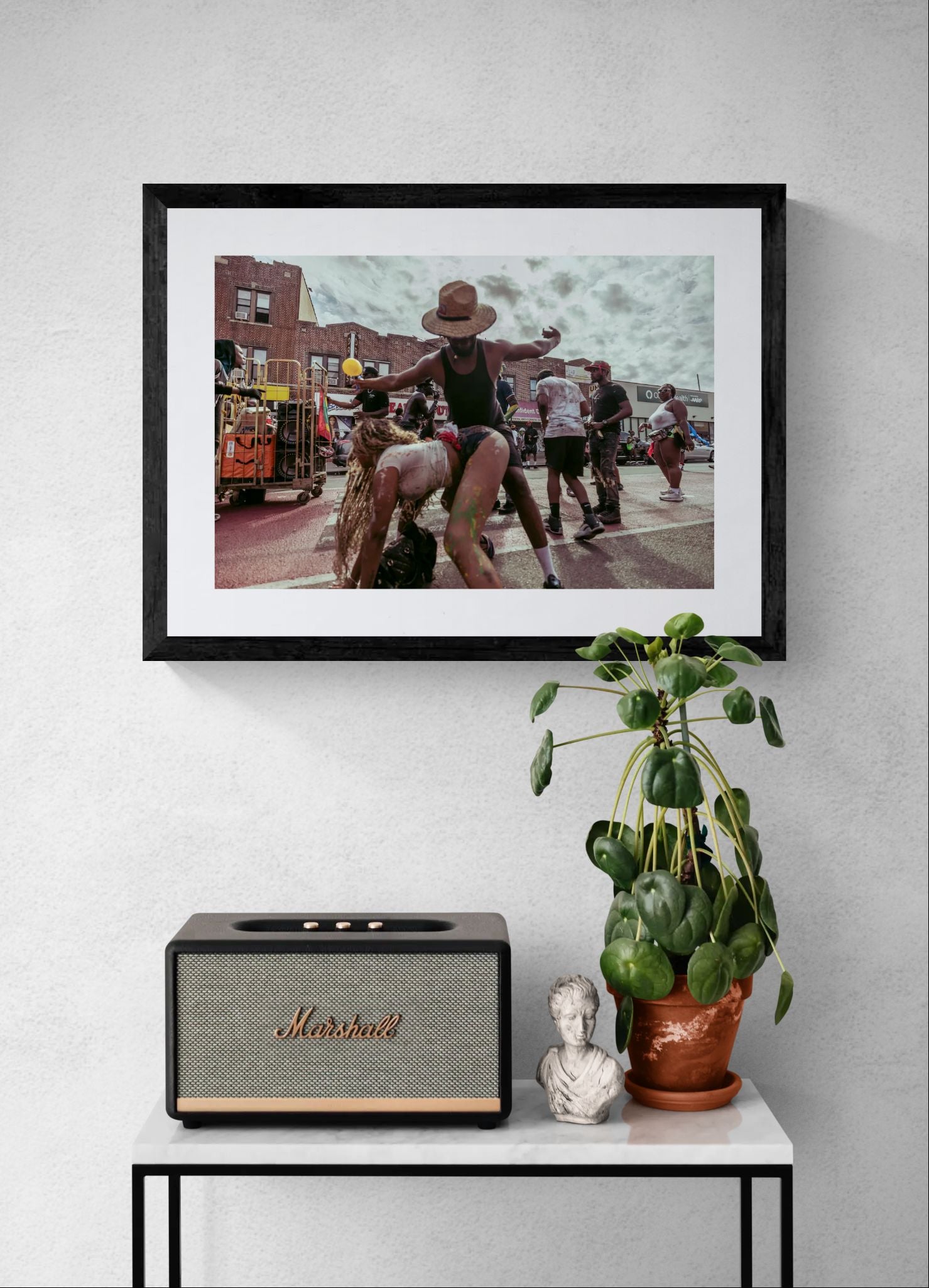 NYC J'Ouvert Straw Hat Dancer, Crown Heights framed in black on a gallery wall with a viewer in a straw hat in front — Good Beans NYC.
