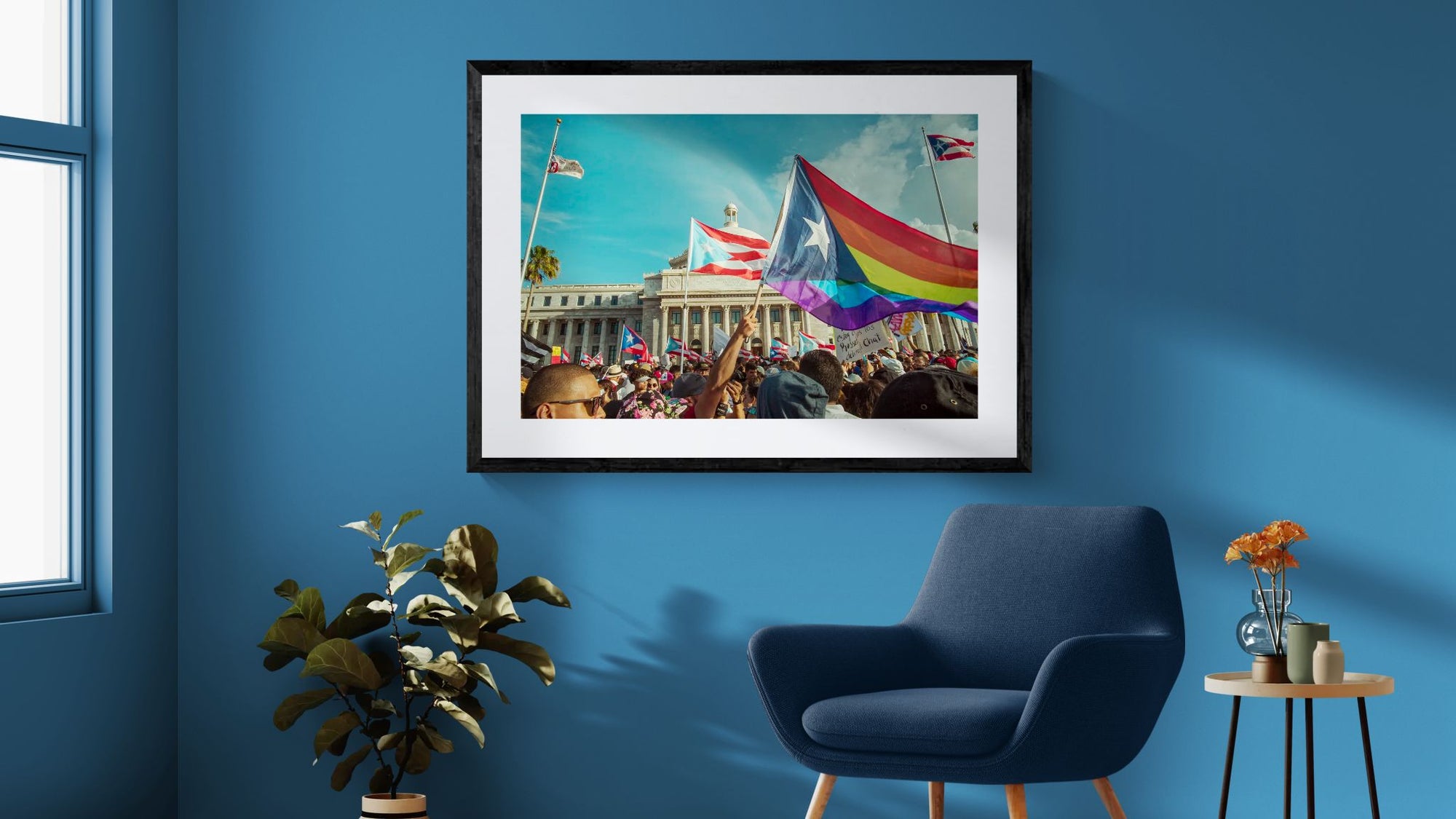 Puerto Rico Capitol Pride Protest, Rainbow Flag framed in black above a beige sofa, sunlit yellow plaster wall — Good Beans NYC.