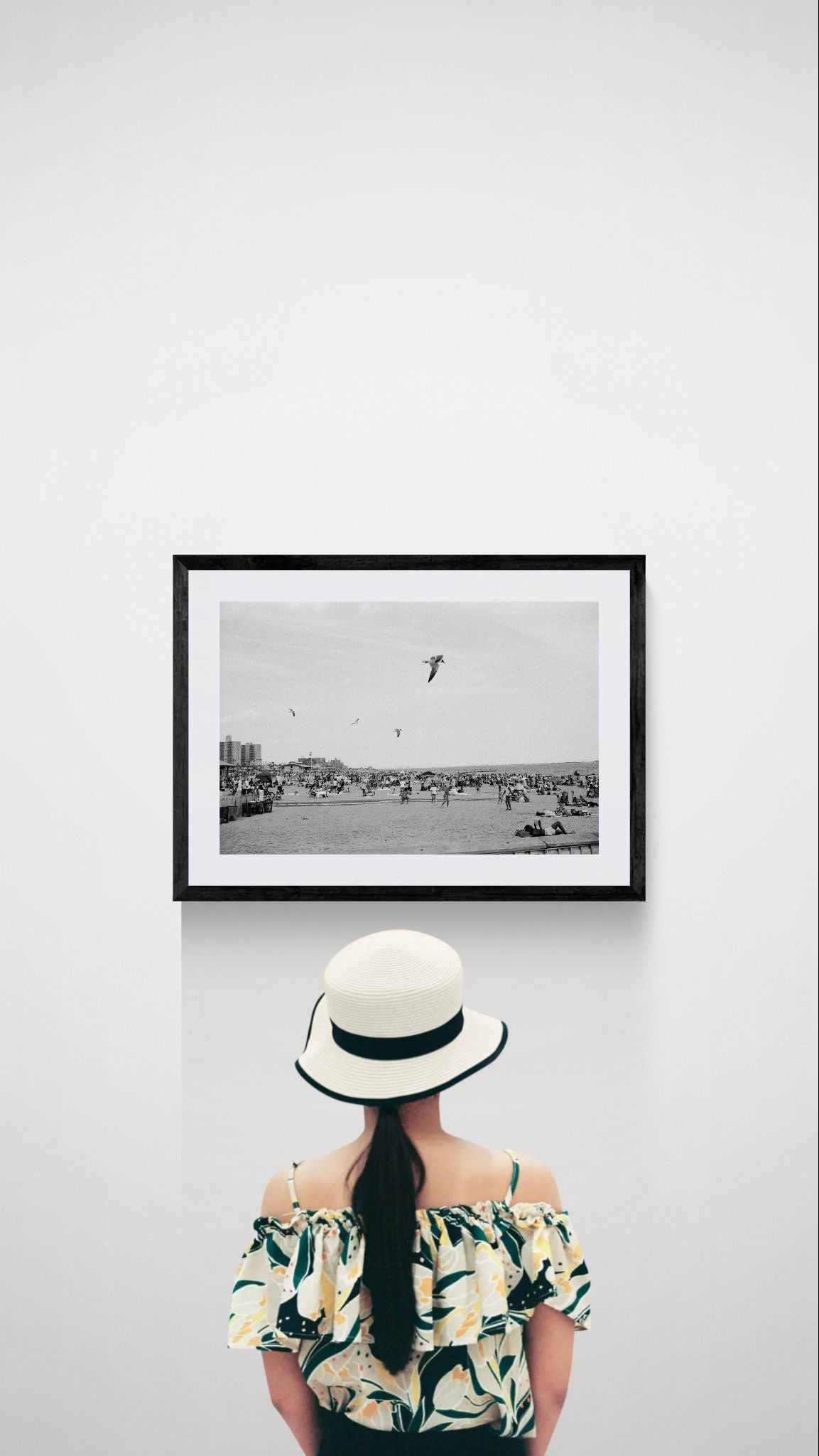 NYC Coney Island Beach Birds, Brooklyn framed in black on a gallery wall with a viewer in a straw hat in front — Good Beans NYC.