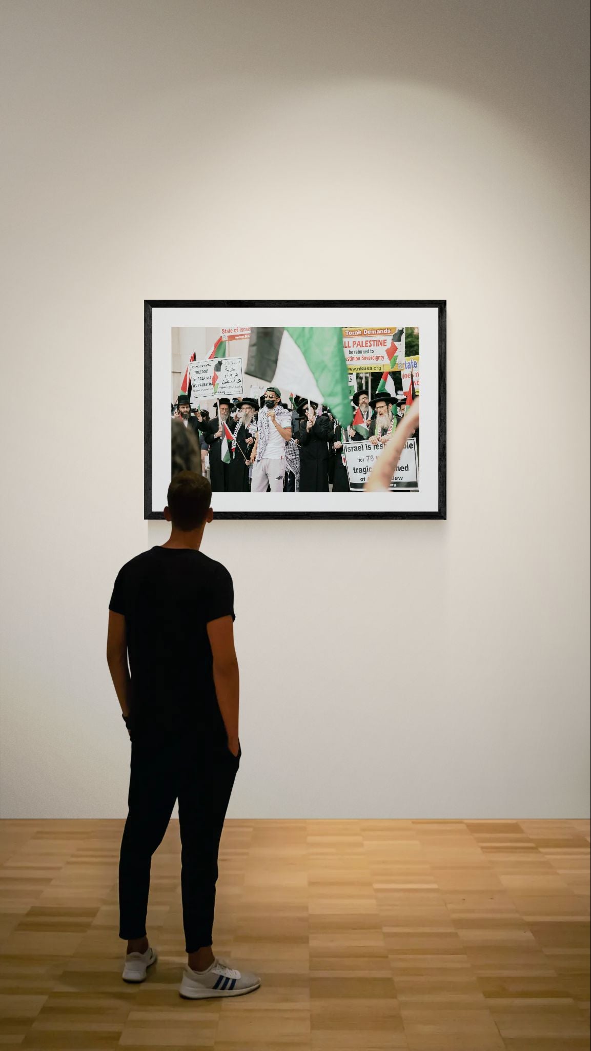 NYC Neturei Karta at Free Palestine Protest framed in black on a gallery wall with a viewer in a straw hat in front — Good Beans NYC.