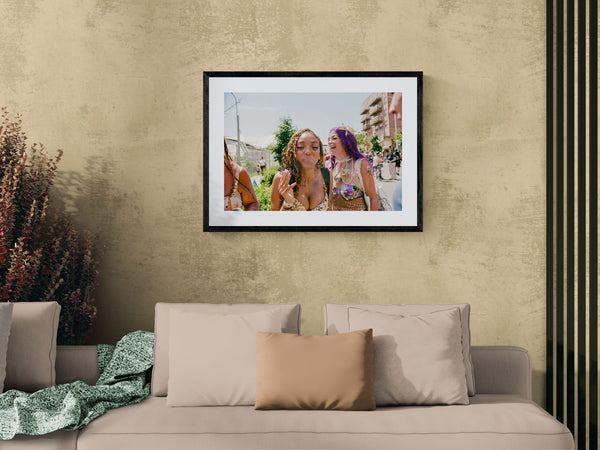 NYC Mermaid Parade Smoking & Laughing, Coney Island framed in black above a beige sofa, sunlit yellow plaster wall — Good Beans NYC.