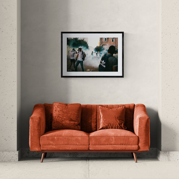 Beirut Tear Gas Protest, October Revolution framed in black above a beige sofa, sunlit yellow plaster wall — Good Beans NYC.