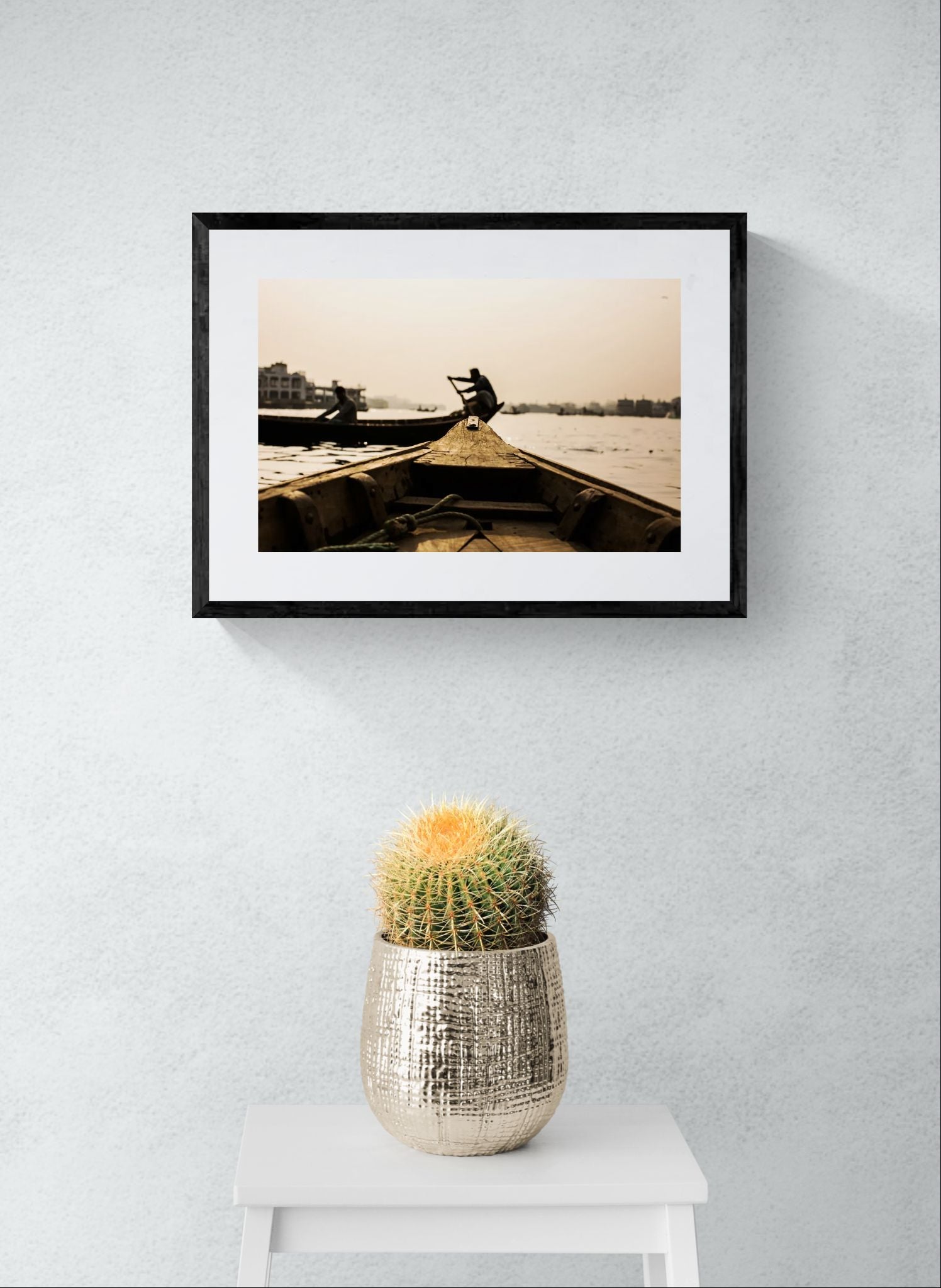 Dhaka Rower at Sunrise, Buriganga River framed in black above a terracotta velvet sofa, gray plaster wall — Good Beans NYC.