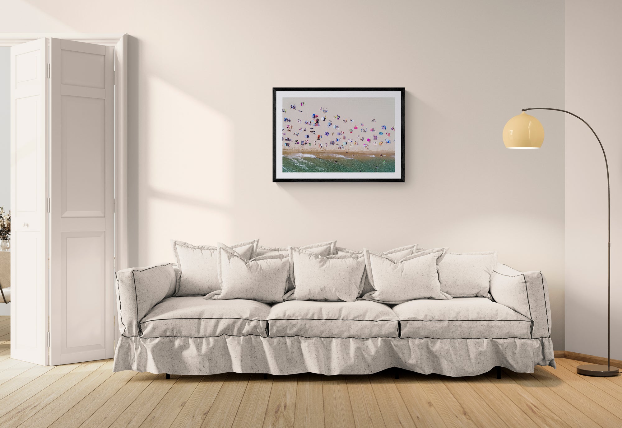 Barcelona from the Air, Barceloneta Beach by Karim Iliya framed in black above a beige sofa, sunlit yellow plaster wall — Good Beans NYC.
