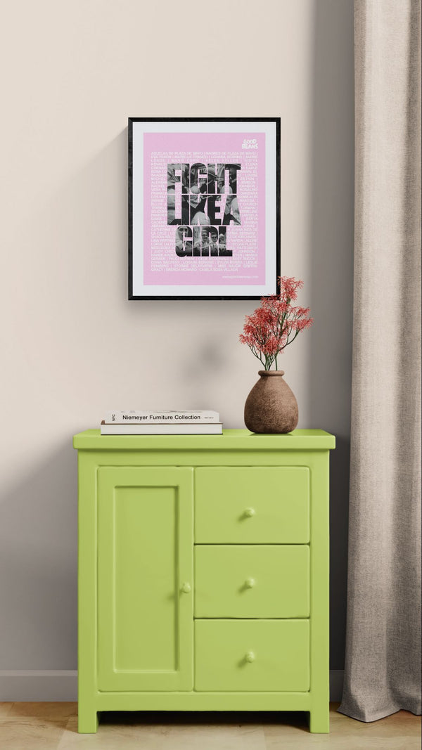 Fight Like a Girl Poster, Plaza de Mayo framed in black on a gallery wall with a viewer in a straw hat in front — Good Beans NYC.