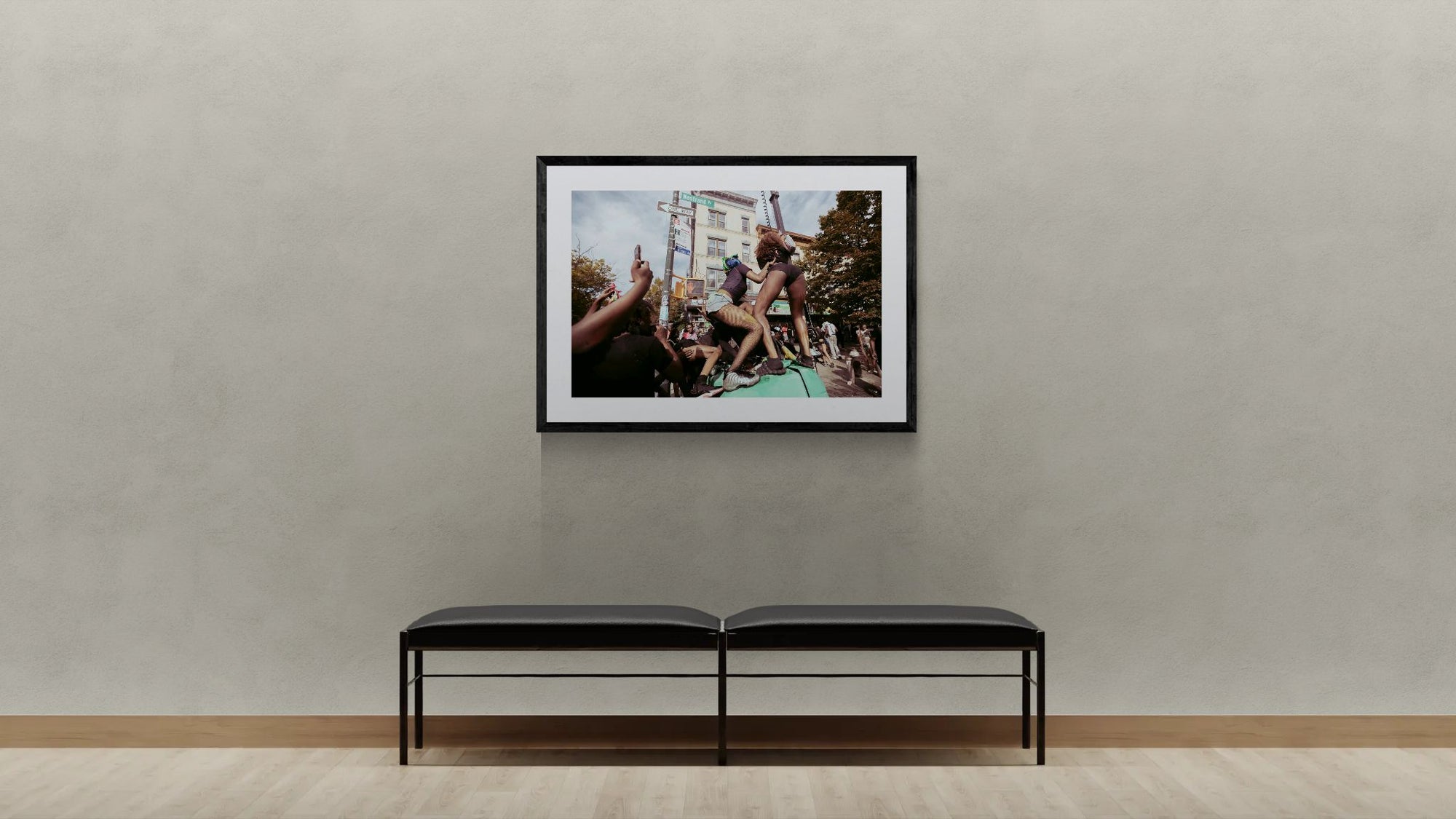 NYC J'Ouvert Twerking, Nostrand Avenue framed in black on a gallery wall with a viewer in a straw hat in front — Good Beans NYC.