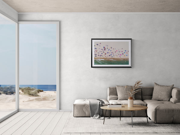 Barcelona from the Air, Barceloneta Beach by Karim Iliya framed in black on a gallery wall with a viewer in a straw hat in front — Good Beans NYC.