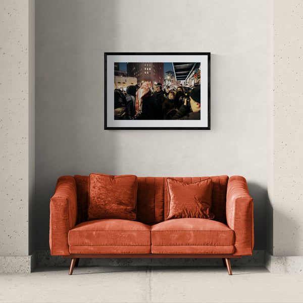 NYC NYPD Megaphone Standoff, Pro Palestine framed in black above a beige sofa, sunlit yellow plaster wall — Good Beans NYC.