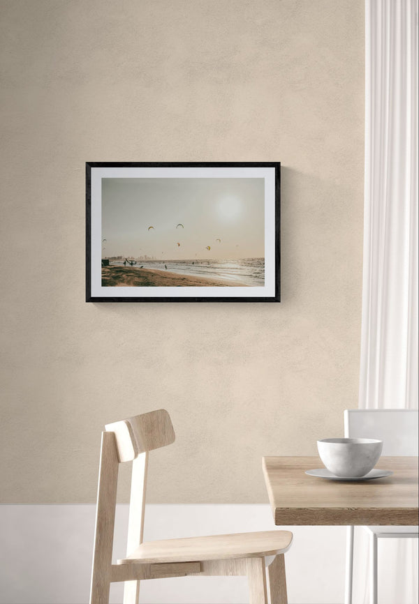 Cartagena Kite Beach — Colombia framed in black above a brown leather sectional, teal wall, gold pendant lamp — Good Beans NYC.