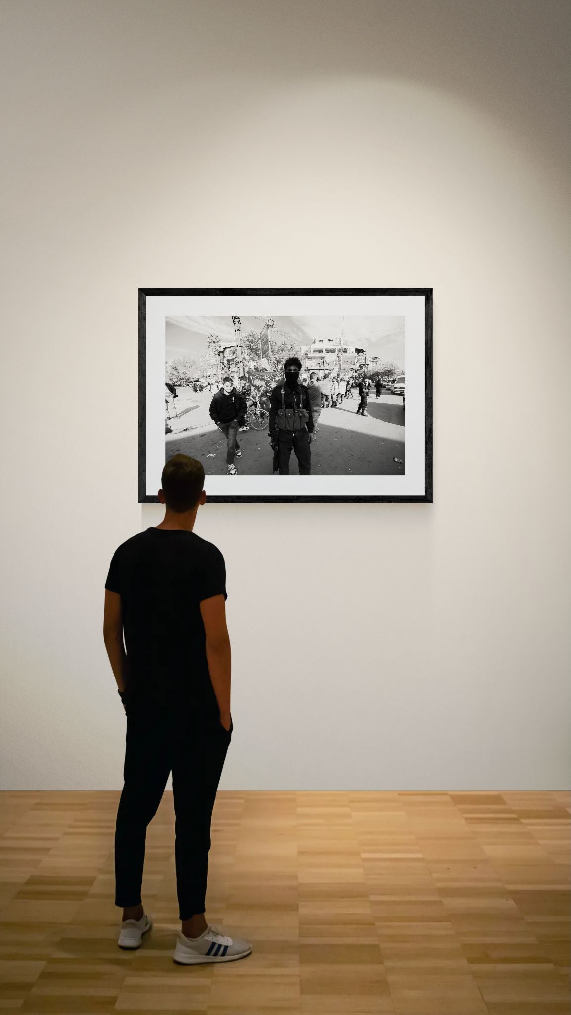 Damascus Masked Armed Fighter at Protest, Syria framed in black on a gallery wall with a viewer in a straw hat in front — Good Beans NYC.
