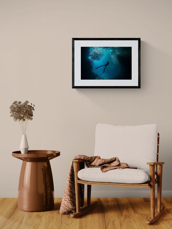 Free Diver Off Mexico Coast, Photo by Karim Iliya framed in black on a gallery wall with a viewer in a straw hat in front — Good Beans NYC.