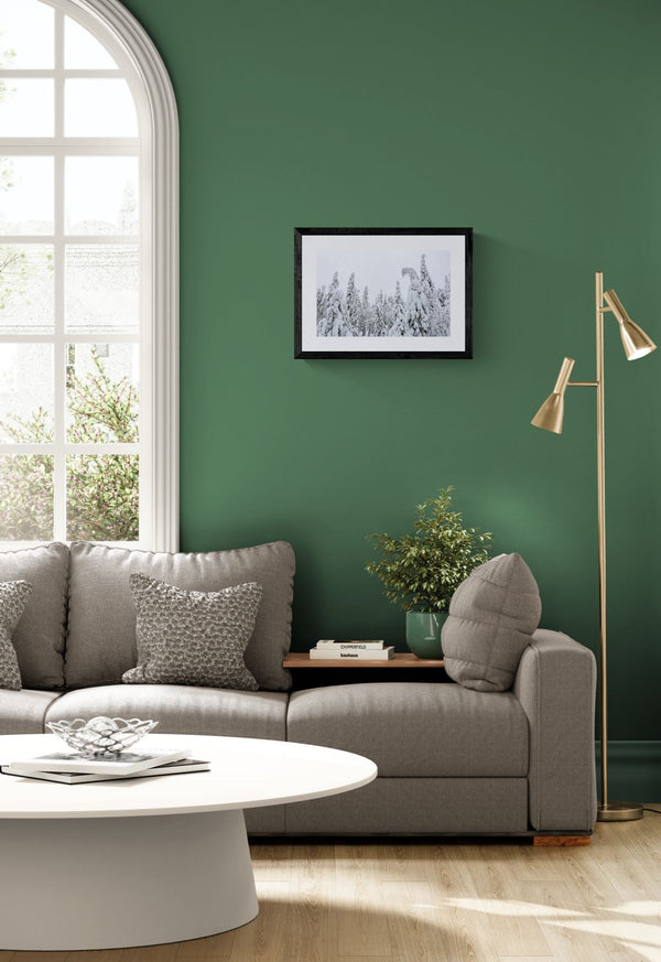 Finland Arctic Circle Snow Forest, Lapland framed in black above a terracotta velvet sofa, gray plaster wall — Good Beans NYC.