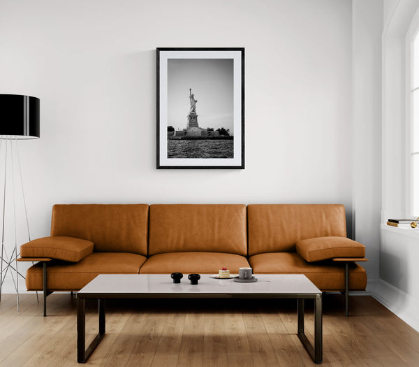NYC Statue of Liberty from the Hudson framed in black above a terracotta velvet sofa, gray plaster wall — Good Beans NYC.