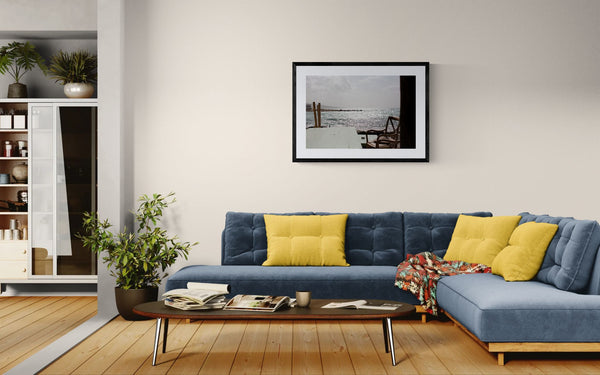 Wing Foiling off the Coast of Byblos, Lebanon framed in black on a gallery wall with a viewer in a straw hat in front — Good Beans NYC.