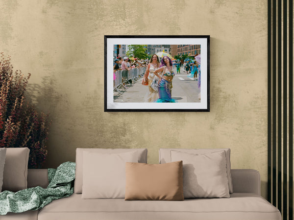 NYC Mermaid Parade Mermaids Posing, Surf Avenue framed in black above a terracotta velvet sofa, gray plaster wall — Good Beans NYC.