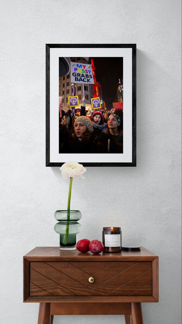 Istanbul Women's March, "My Pussy Grabs Back" Sign framed in black on a gallery wall with a side-profile viewer in a dark coat — Good Beans NYC.