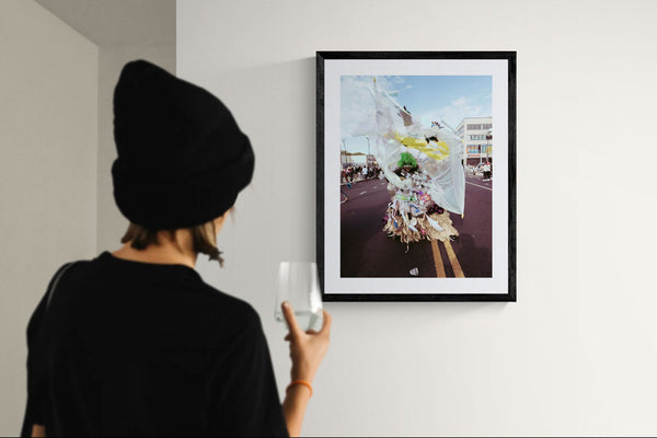 NYC J'Ouvert Green Woman Trash Costume, Flatbush framed in black on a gallery wall with a side-profile viewer in a dark coat — Good Beans NYC.