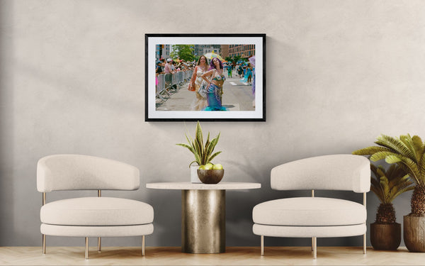 NYC Mermaid Parade Mermaids Posing, Surf Avenue framed in black on a gallery wall with a viewer in a straw hat in front — Good Beans NYC.