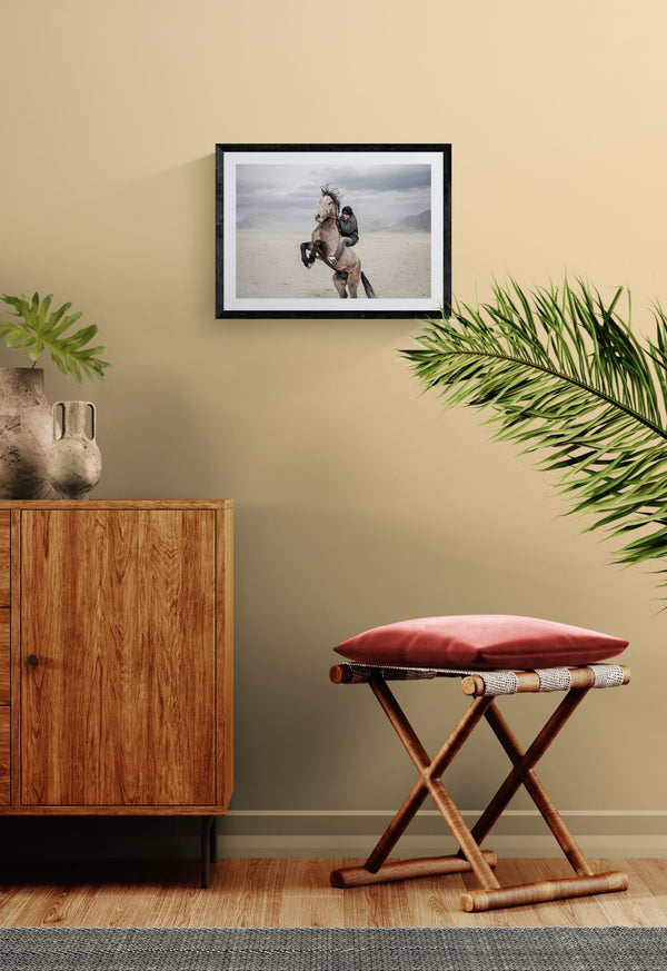 Mongolian Horse Rider, Bayan-Ölgii framed in black above a beige sofa, sunlit yellow plaster wall — Good Beans NYC.