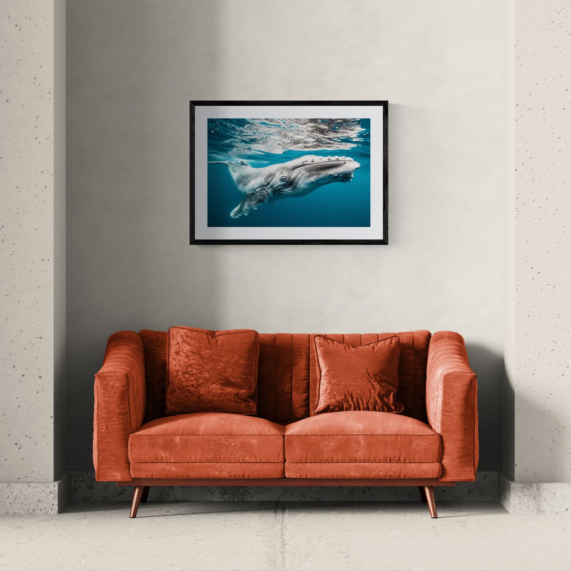 Baby Humpback Whale off the Coast of Tonga, Photo by Karim Iliya framed in black above a beige sofa, sunlit yellow plaster wall — Good Beans NYC.