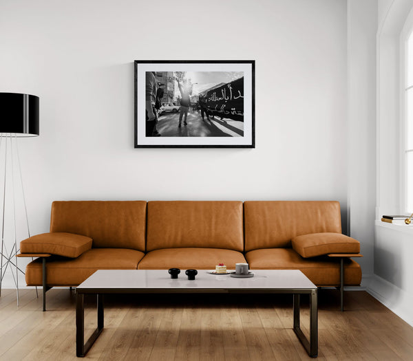 Damascus Raised Fist Protest, Syria framed in black above a beige sofa, sunlit yellow plaster wall — Good Beans NYC.