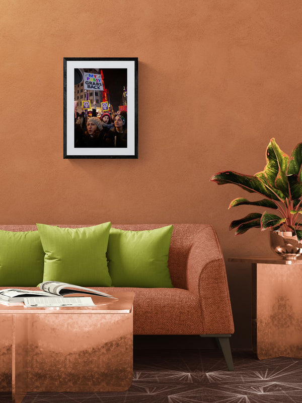 Istanbul Women's March, "My Pussy Grabs Back" Sign framed in black above a terracotta velvet sofa, gray plaster wall — Good Beans NYC.