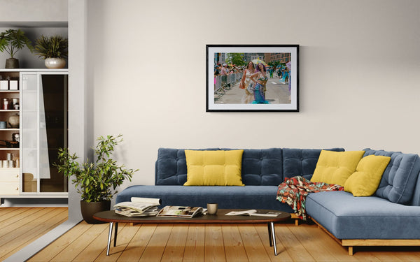 NYC Mermaid Parade Mermaids Posing, Surf Avenue framed in black above a beige sofa, sunlit yellow plaster wall — Good Beans NYC.