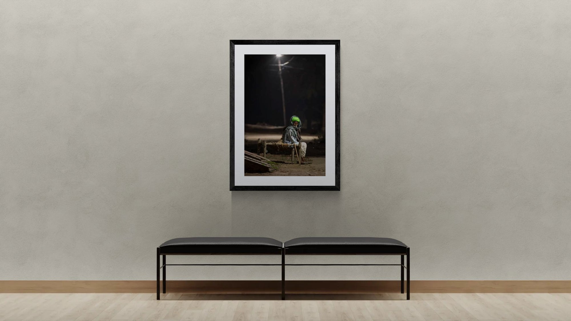 India Man Under Streetlight, Jodhpur framed in black on a gallery wall with a viewer in a straw hat in front — Good Beans NYC.