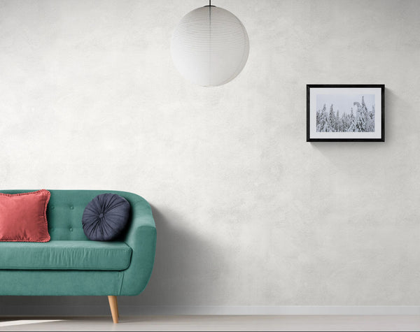 Finland Arctic Circle Snow Forest, Lapland framed in black above a beige sofa, sunlit yellow plaster wall — Good Beans NYC.